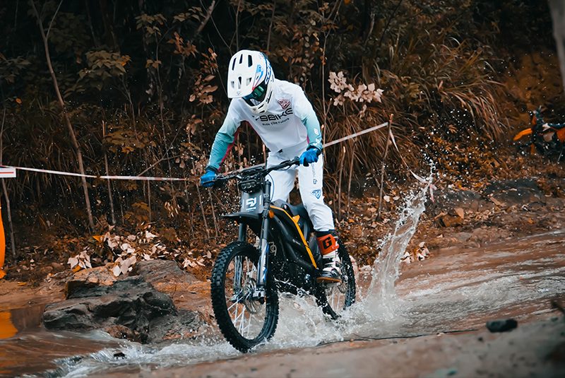 Rider splashing through water on an electric dirt bike